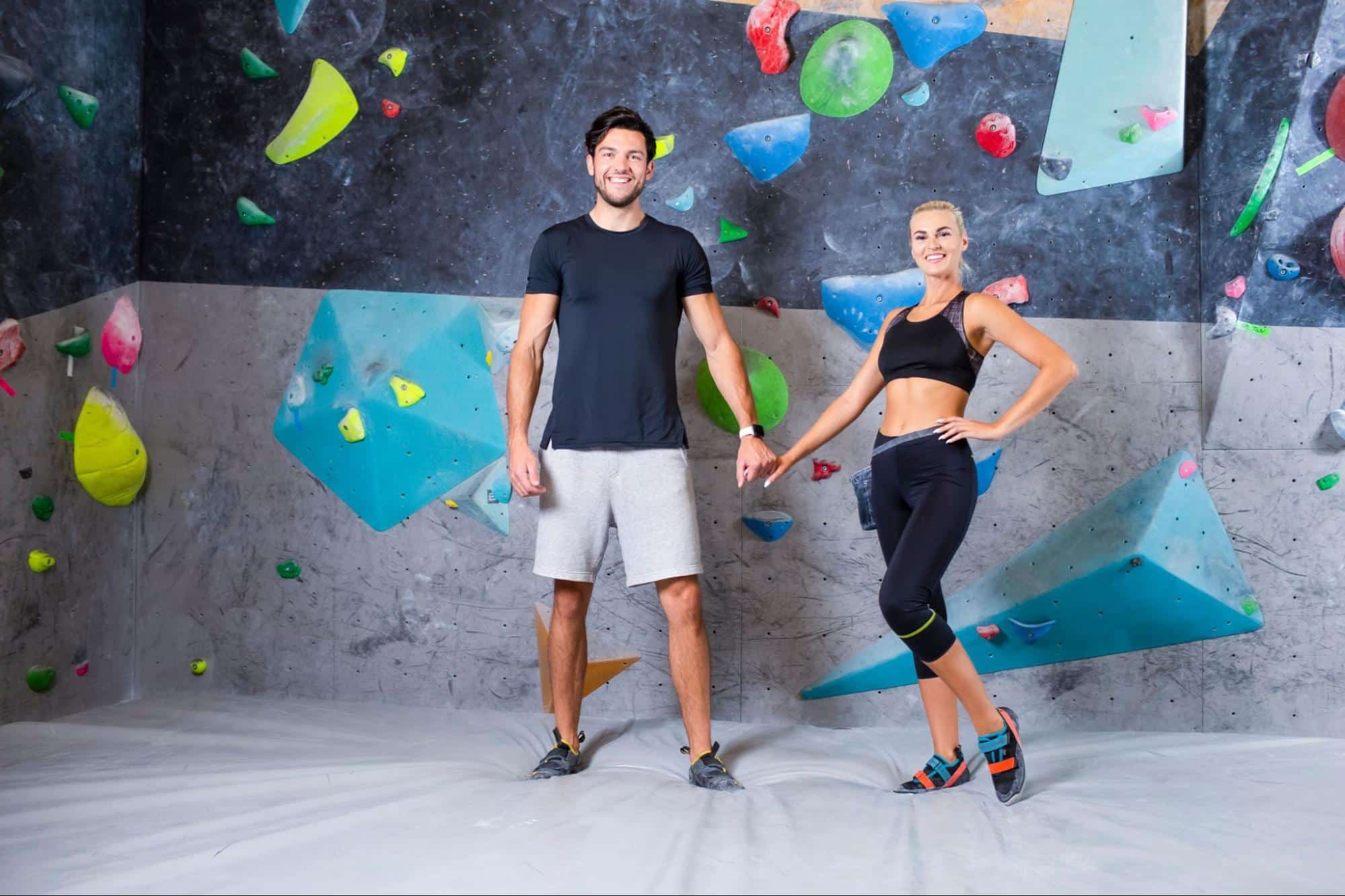 couple standing in front of rock wall before rock climbing