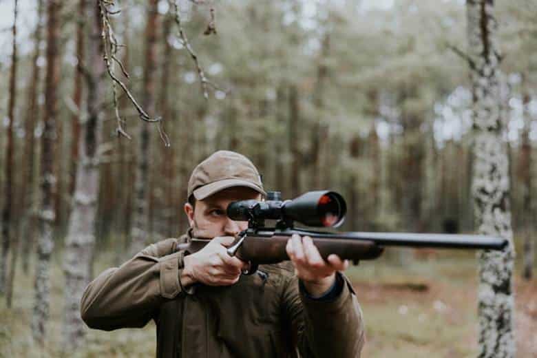 A Hunter Aims His Rifle That Has A Scope On It.
