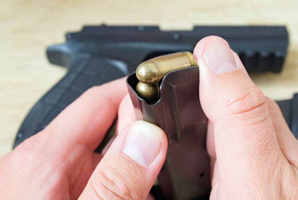 Persons hands holding and loading 9mm bullets in the pistol