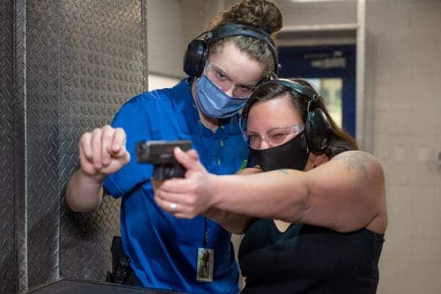 trainer at the range 702 in las vegas showing lady how to shoot pistol