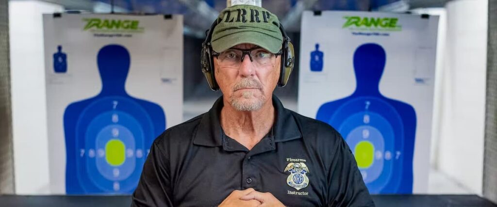 An older gentleman at The Range 702 wearing ear protectors with shooting targets in the background.