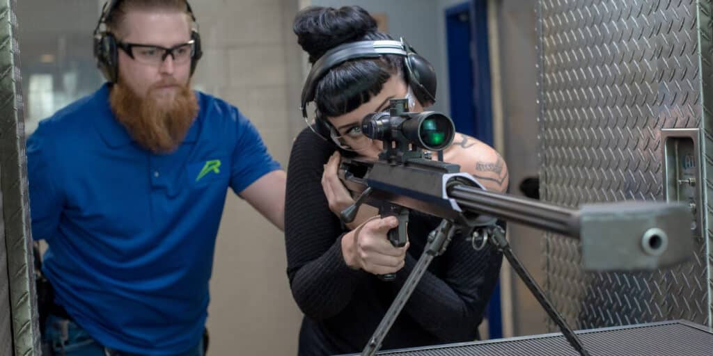 person firing a 50 cal gun with trainer