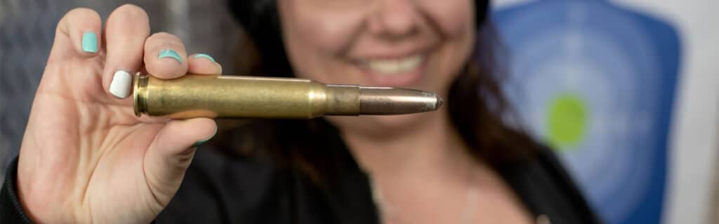 woman holding 50 cal ammo