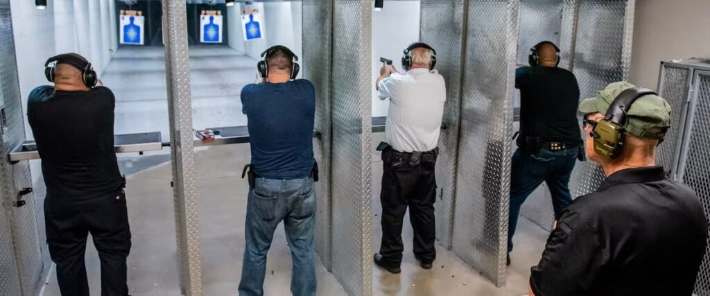 Four men are shooting at The Range 702 in a row, as an instructor watches from behind.
