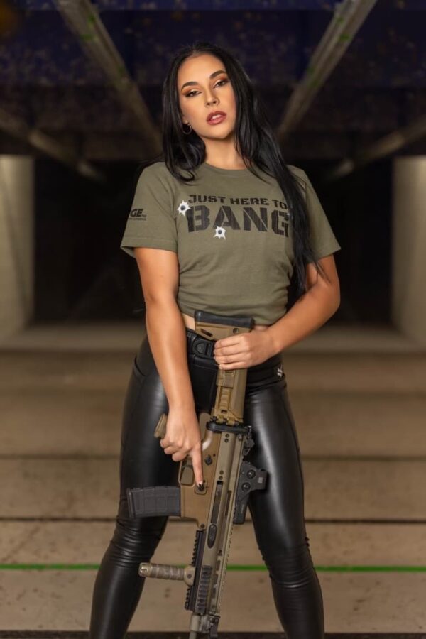 A woman wearing a The Range 702 t-shirt that says "Just here to bang."