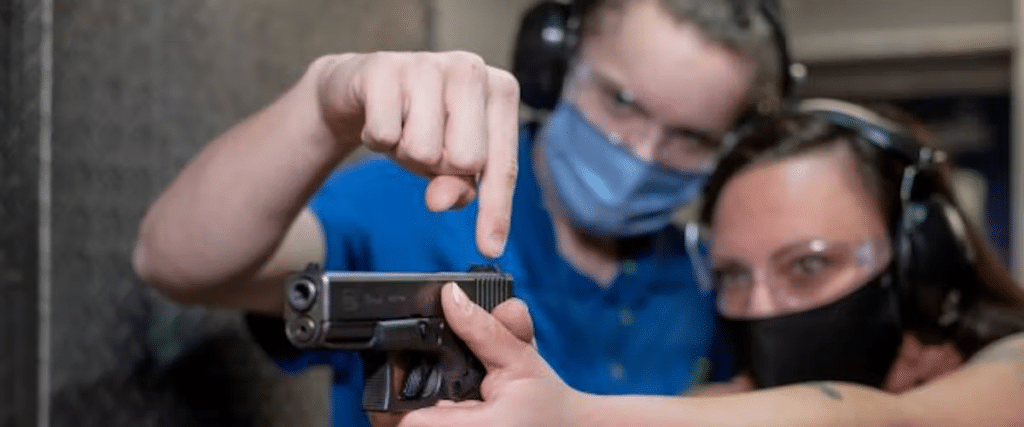 An instructor teaches a woman how to shoot.