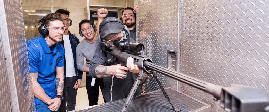 Four men taking turns shooting with their instructor watching.