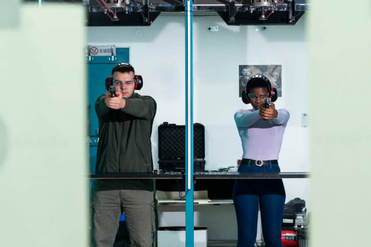 a male and female shoot next to each other at a gun range