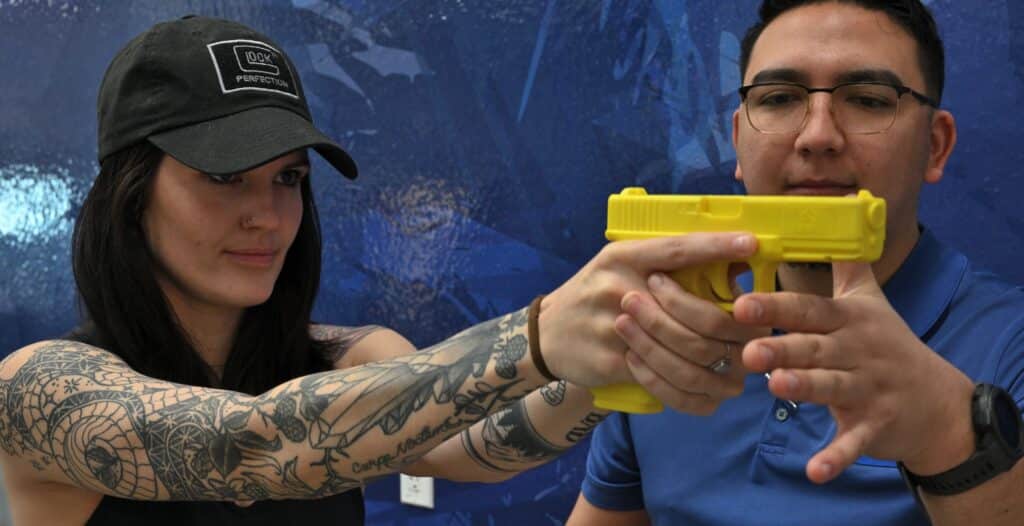 A firearms instructor at The Range 702 shooting range in Las Vegas teaches a client about proper sight alignment.