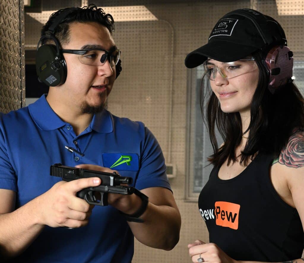 A firearms instructor at The Range 702 shooting range in Las Vegas shows a student how to operate a modern semi-automatic pistol.