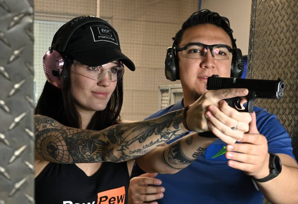 A woman operates a semi-automatic handgun at The Range 702's shooting range in Las Vegas with a firearms instructor.