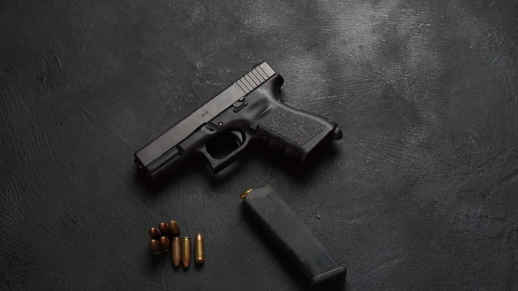 Handgun on black background with bullets underneath it